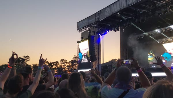 a whole rave crowd at Breakaway Music Festival dancing to Deadmau5 as the sun is setting down